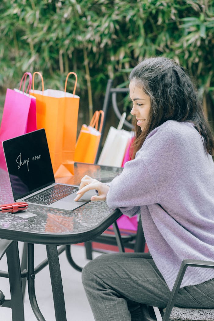 Crafting Captivating Headlines: Your awesome post title goes here A woman shops online using a laptop outdoors, surrounded by colorful shopping bags, representing modern retail therapy.